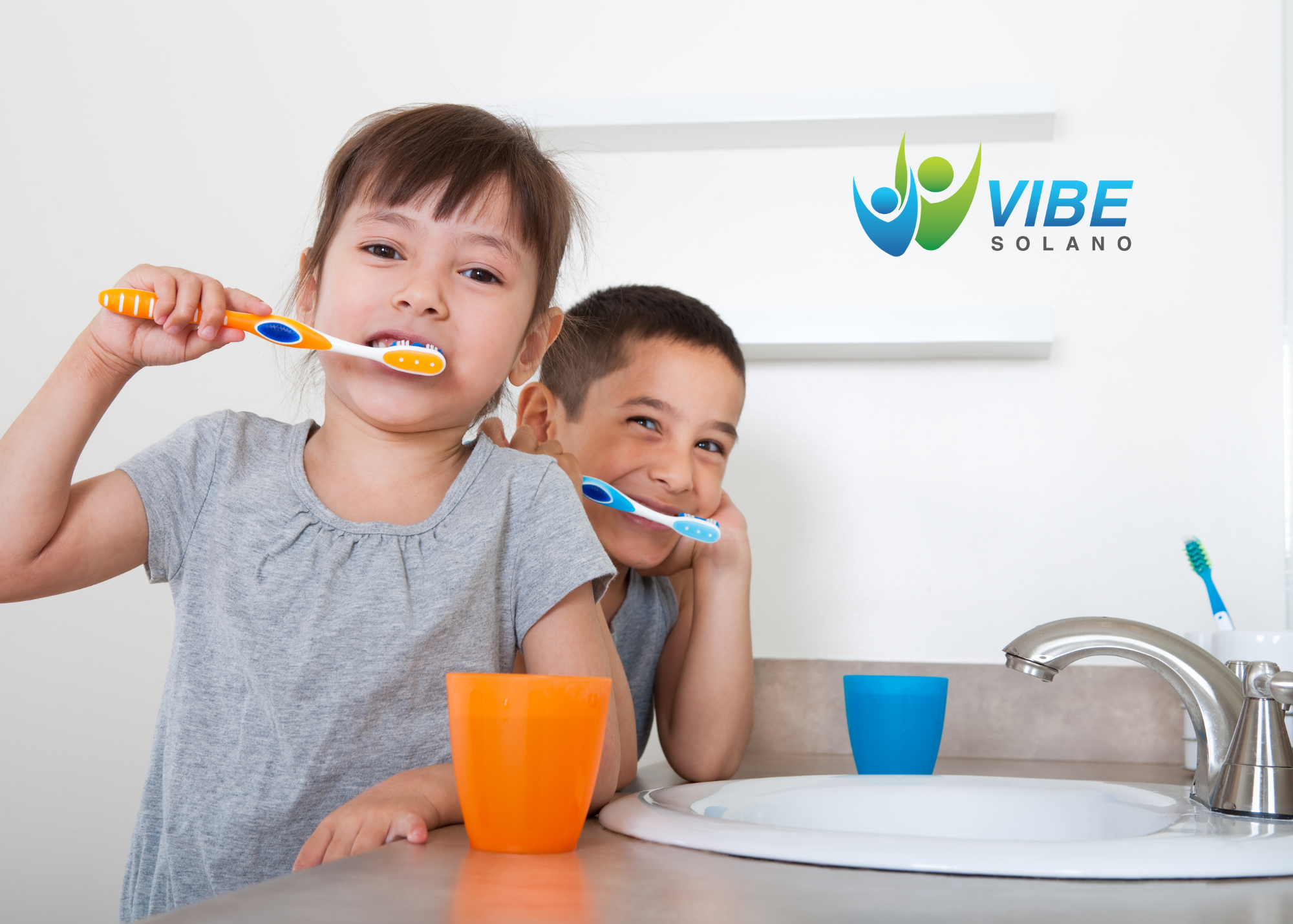 Two children brushing their teeth in front of a bathroom sink